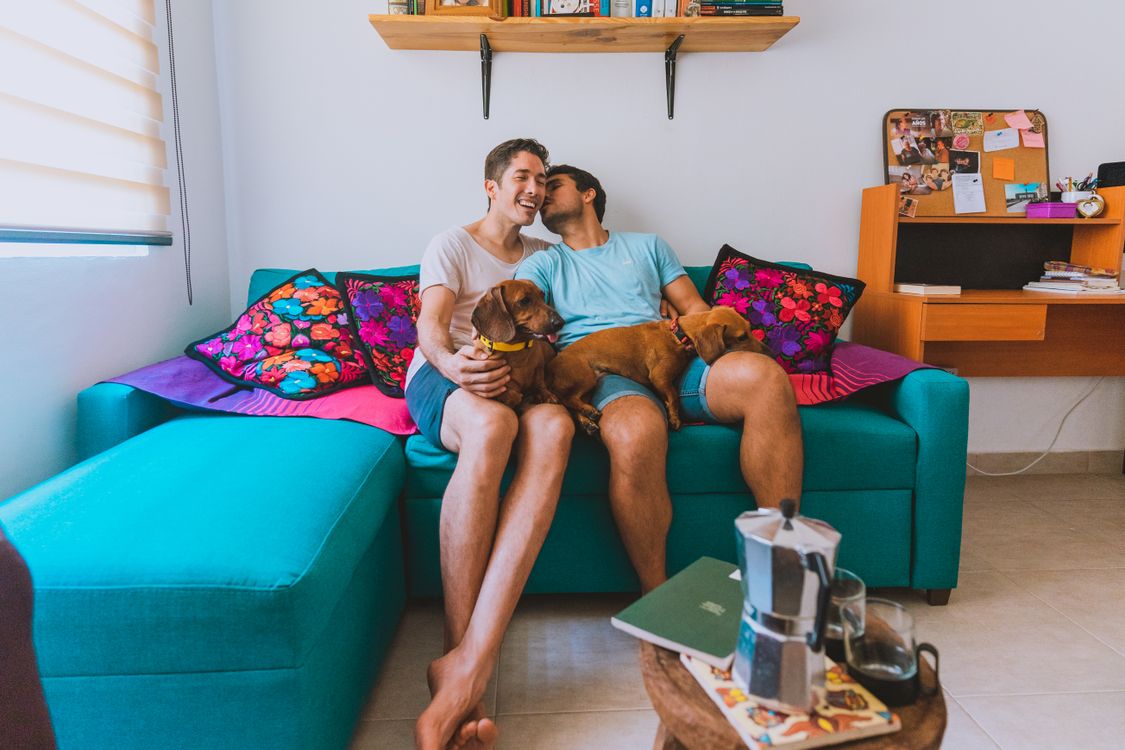 A Couple Sitting on a Couch With Their Dogs - new ruling for apartment pets